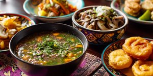 Colorful vegan Peruvian dishes including quinoa soup, mushroom ceviche and picarones on a table