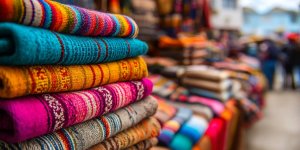 Colorful traditional Peruvian alpaca wool textiles and handicrafts displayed at vibrant Sacred Valley market with local indigenous vendors