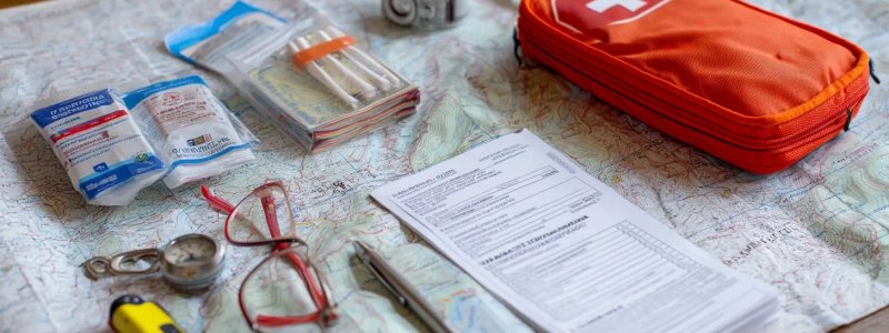 Travel safety checklist with first aid kit, emergency contacts, travel insurance documents, and safety gear arranged on map of Peru