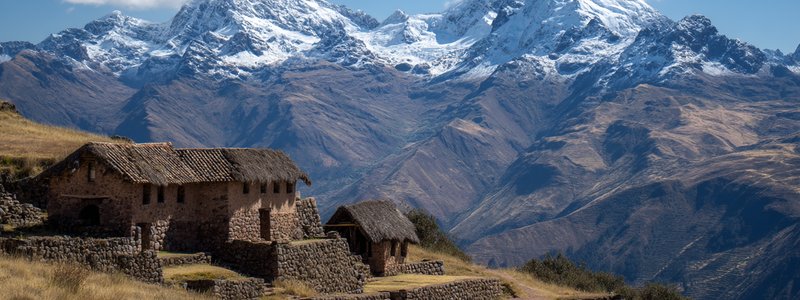 Hikers overlooking the terraces and stone buildings of Huchuy Qosqo with snow-capped peaks behind
