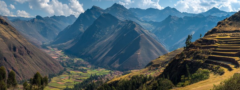 Panoramic view of Sacred Valley with terraced mountains, ancient Inca ruins of Pisac overlooking the green valley with traditional Andean villages below