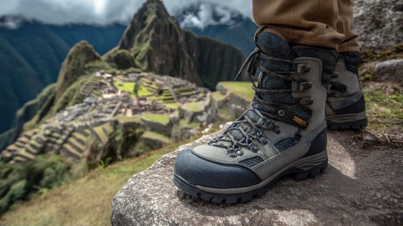 Professional trekking boots with gaiters on ancient Inca stone steps at Machu Picchu with detailed view of hiking gear and mountain trail equipment