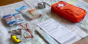 Travel safety checklist with first aid kit, emergency contacts, travel insurance documents, and safety gear arranged on map of Peru