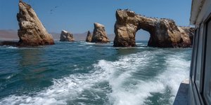 Boat approaching the Ballestas Islands with sea lions and arches visible in Paracas, Peru