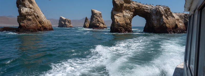 Boat approaching the Ballestas Islands with sea lions and arches visible in Paracas, Peru