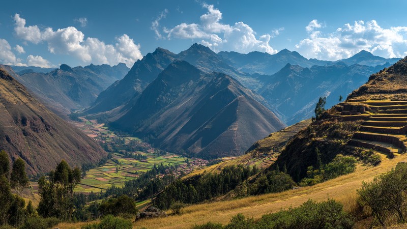 Panoramic view of Sacred Valley with terraced mountains, ancient Inca ruins of Pisac overlooking the green valley with traditional Andean villages below