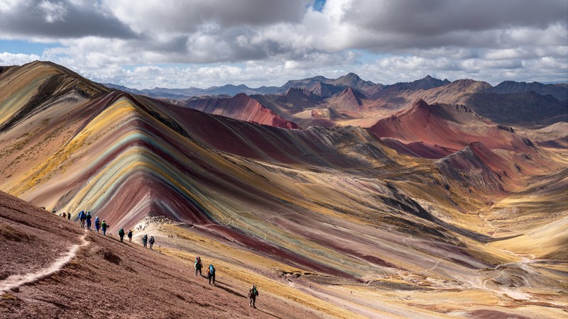 Rainbow Mountain’s colorful striped slopes with hikers in the foreground