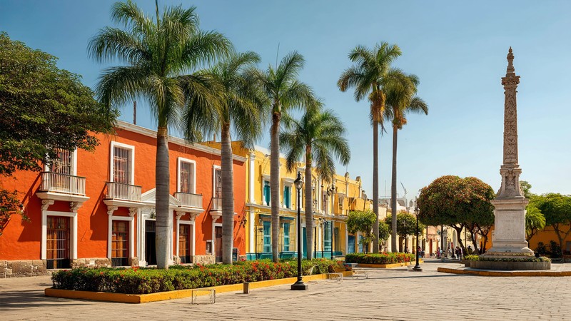 Colourful colonial buildings around Trujillo’s Plaza de Armas with palm trees and the Liberty Monument