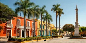 Colourful colonial buildings around Trujillo’s Plaza de Armas with palm trees and the Liberty Monument
