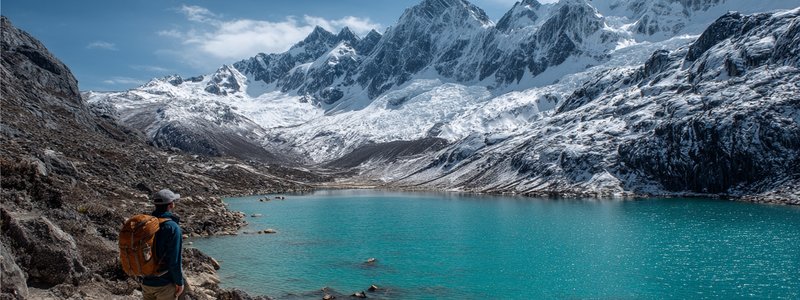 Trekker looking at a turquoise lake and snow-capped peaks on the Santa Cruz Trek